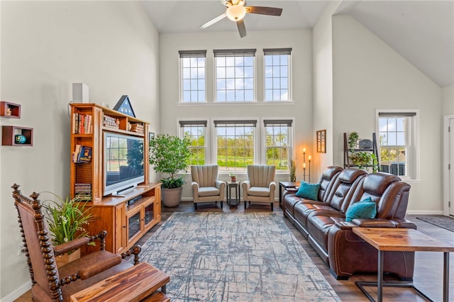 living area with wood finished floors, baseboards, ceiling fan, and high vaulted ceiling