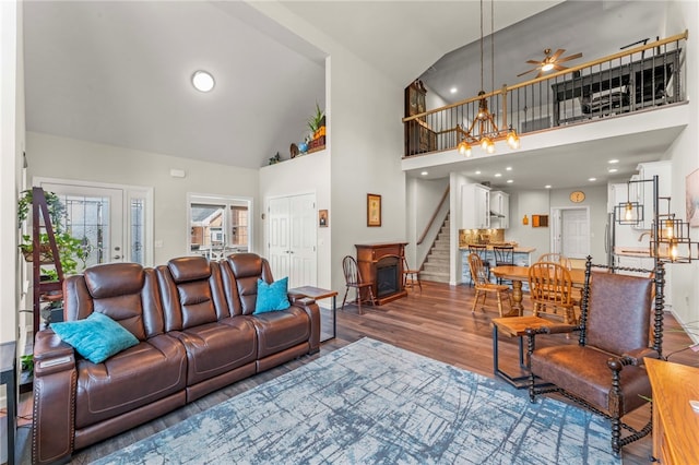 living room with stairway, high vaulted ceiling, a ceiling fan, and wood finished floors