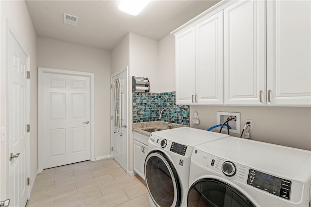 washroom featuring a sink, separate washer and dryer, cabinet space, visible vents, and baseboards