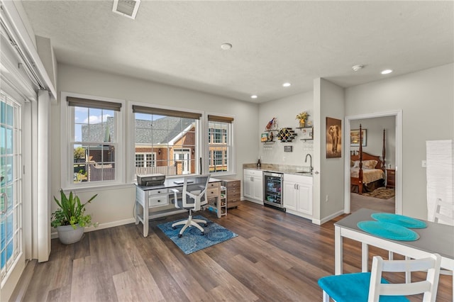 home office with a sink, wine cooler, wet bar, visible vents, and dark wood-style floors