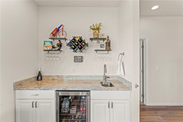 bar with wood finished floors, indoor wet bar, a sink, baseboards, and wine cooler