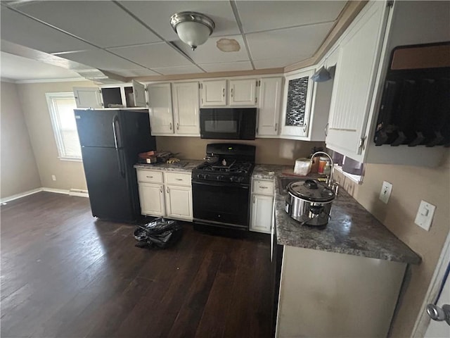 kitchen with a sink, a paneled ceiling, black appliances, white cabinets, and dark wood-style floors
