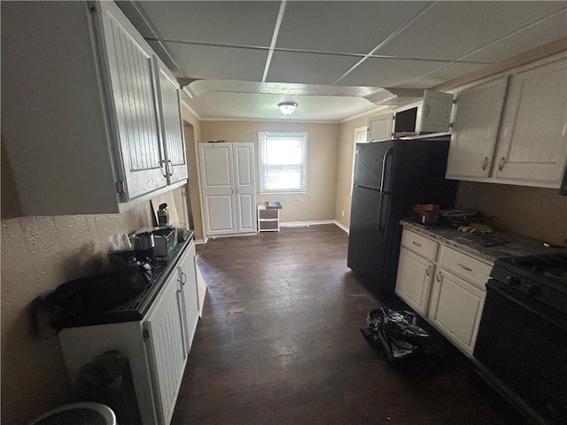 kitchen with freestanding refrigerator, gas stove, and white cabinets