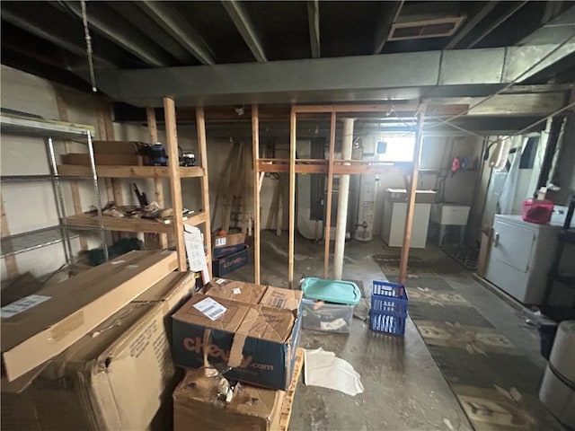 unfinished basement featuring water heater, visible vents, and washer / clothes dryer