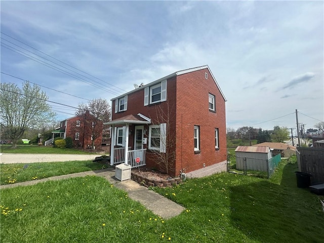 view of front of property featuring fence, a front lawn, and brick siding