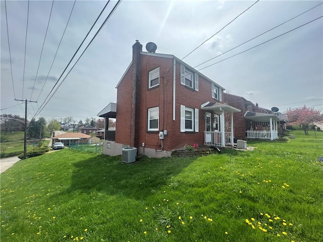 view of property exterior featuring a yard, brick siding, a chimney, and cooling unit