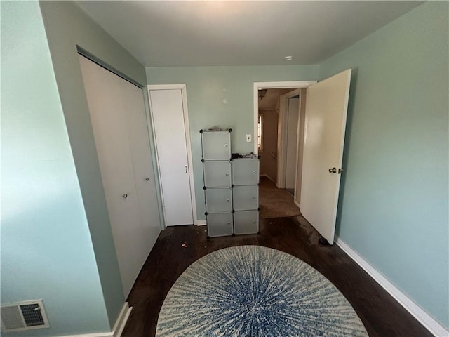 hallway featuring baseboards, visible vents, and wood finished floors