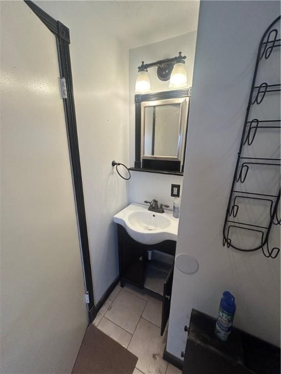 bathroom featuring baseboards, tile patterned flooring, and a sink