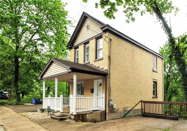 view of side of property featuring covered porch and brick siding