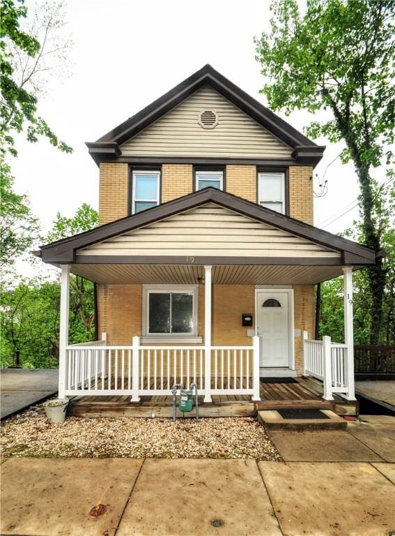 view of front facade with brick siding and covered porch