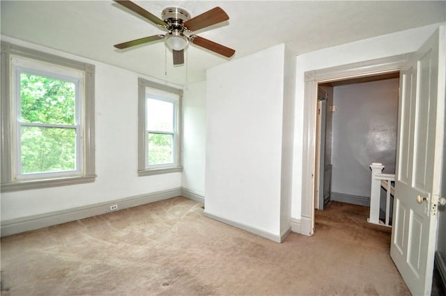 spare room with light carpet, baseboards, and plenty of natural light