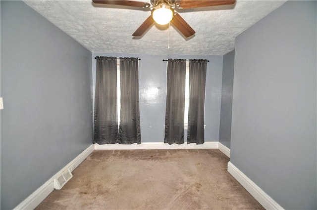 carpeted spare room with a ceiling fan, baseboards, and a textured ceiling