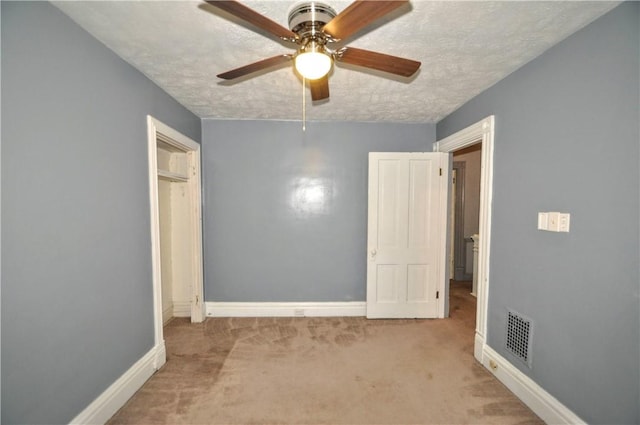 unfurnished bedroom with carpet, a textured ceiling, baseboards, and a ceiling fan