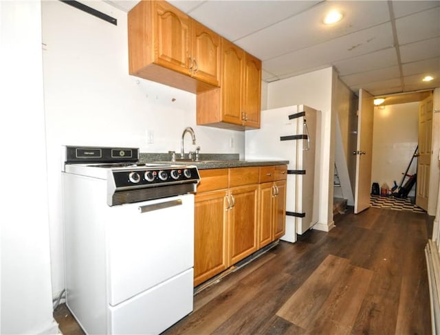 kitchen with range with gas cooktop, dark wood-style flooring, dark countertops, a sink, and freestanding refrigerator