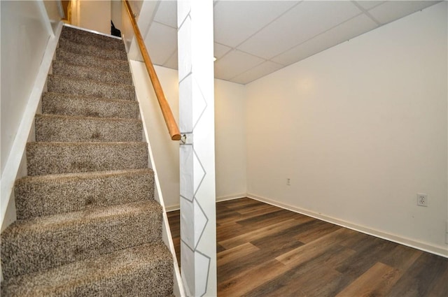 stairs featuring a drop ceiling, wood finished floors, and baseboards