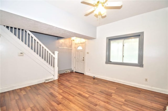 foyer with stairway, wood finished floors, a ceiling fan, and baseboards