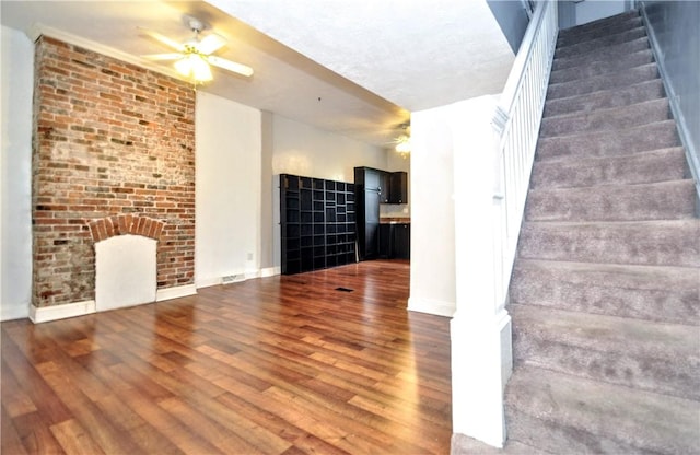 unfurnished living room with ceiling fan, stairway, wood finished floors, and baseboards