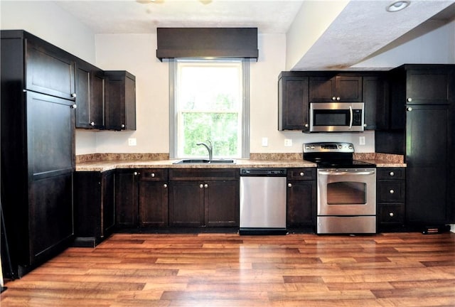 kitchen featuring stainless steel appliances, a sink, light wood-type flooring, and light countertops