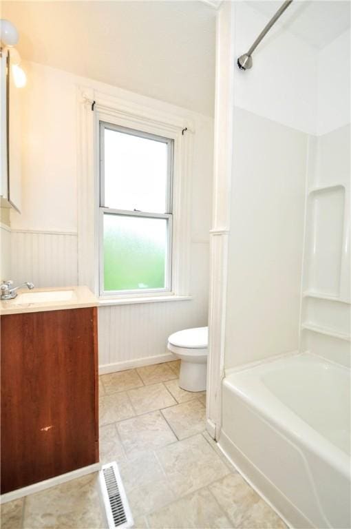 bathroom with toilet, wainscoting, shower / bathtub combination, and vanity