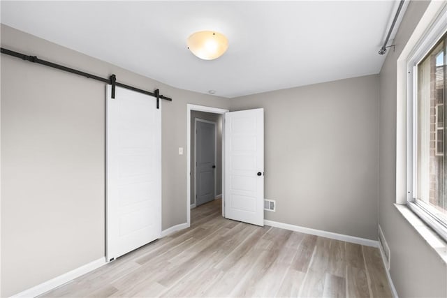 3606 Churchview Ave, Baldwin Boro, PA 15236 - unfurnished bedroom featuring multiple windows, a barn door, and light wood-style flooring