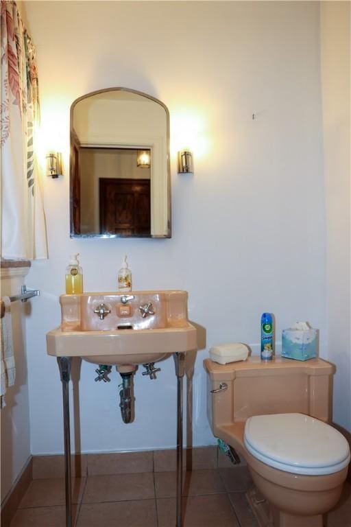 bathroom with toilet, baseboards, and tile patterned flooring
