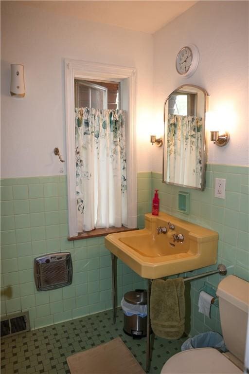 bathroom with tile walls, wainscoting, visible vents, a sink, and tile patterned floors