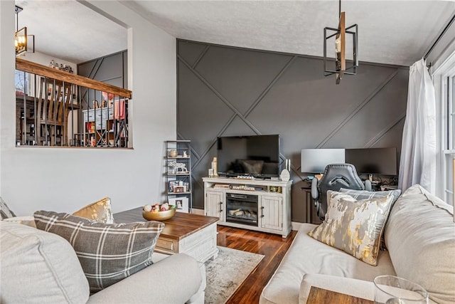 living area featuring a chandelier, a glass covered fireplace, and dark wood-style floors