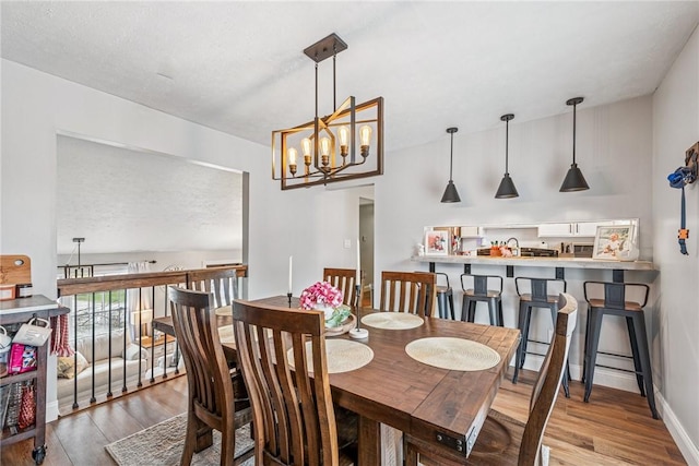 dining space with vaulted ceiling, an inviting chandelier, and wood finished floors