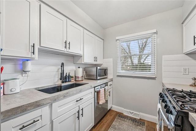 kitchen with a sink, wood finished floors, light countertops, white cabinets, and appliances with stainless steel finishes