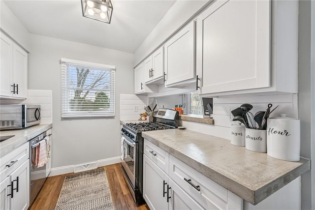 kitchen featuring stainless steel appliances, white cabinets, light countertops, light wood-style floors, and decorative backsplash