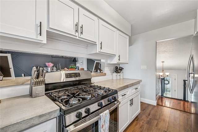 kitchen with stainless steel gas stove, white cabinetry, dark wood-style flooring, baseboards, and light countertops