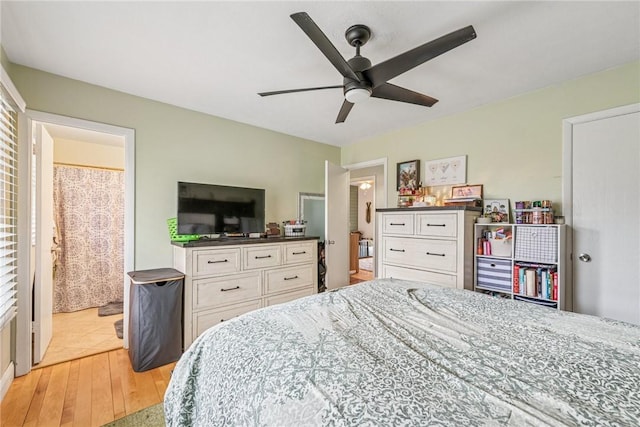 bedroom with light wood-style flooring, ceiling fan, and connected bathroom