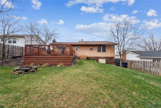 rear view of house featuring a yard, a wooden deck, a fire pit, and a fenced backyard