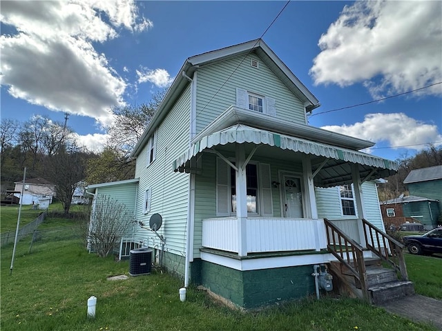 view of front of home with covered porch, fence, a front lawn, and cooling unit