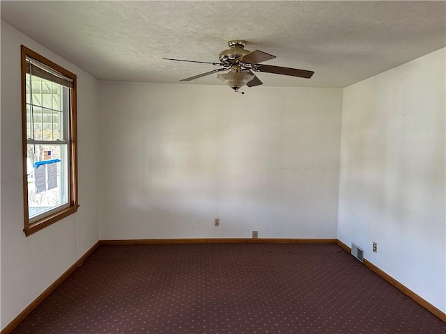carpeted empty room featuring visible vents, baseboards, and a ceiling fan