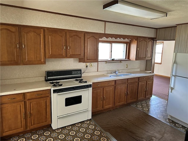 kitchen featuring light countertops, brown cabinets, a sink, and white appliances