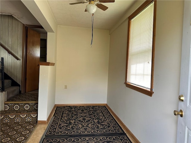 interior space with stairway, baseboards, and ceiling fan