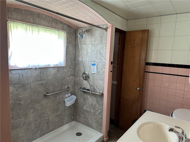full bath with tile walls, a shower stall, and a sink