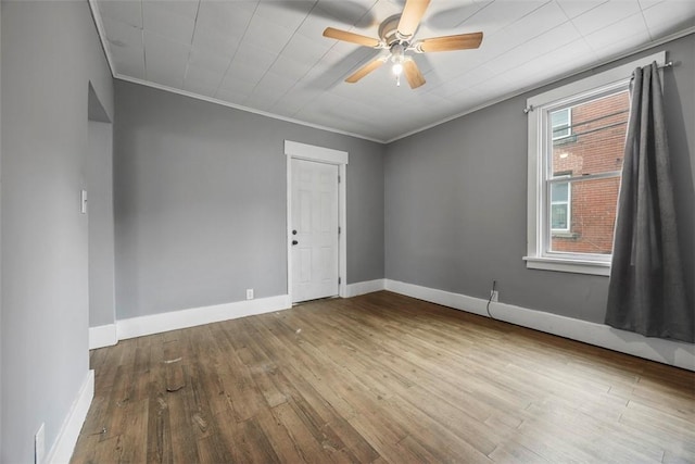 spare room featuring baseboards, a ceiling fan, ornamental molding, and hardwood / wood-style flooring