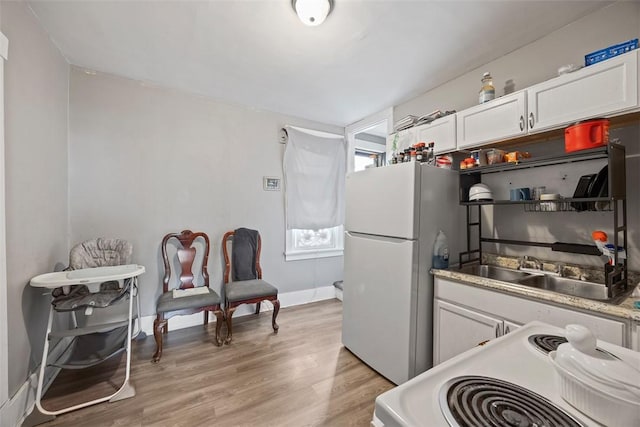 kitchen with a sink, white cabinets, light wood-type flooring, white appliances, and light countertops
