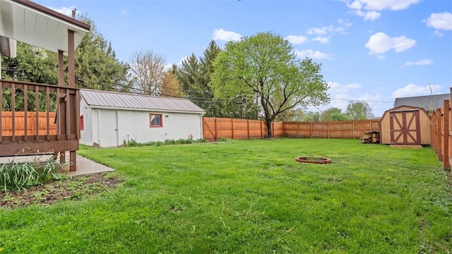 view of yard featuring an outdoor fire pit, an outdoor structure, a fenced backyard, and a storage unit