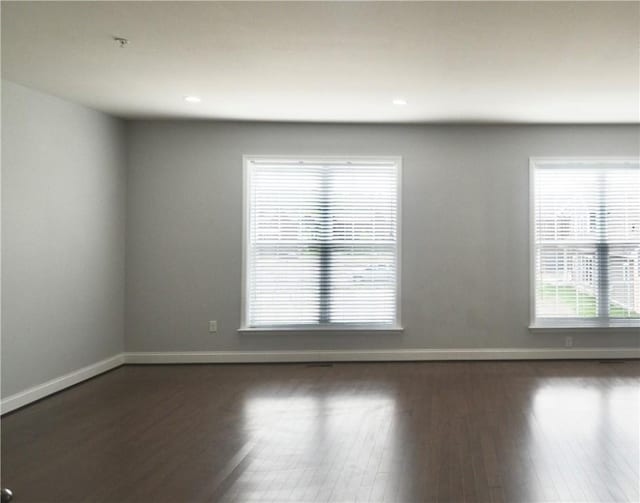 spare room featuring baseboards, dark wood-style floors, and recessed lighting