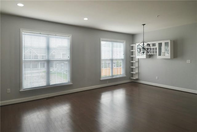 unfurnished dining area featuring baseboards, an inviting chandelier, recessed lighting, and dark wood-type flooring