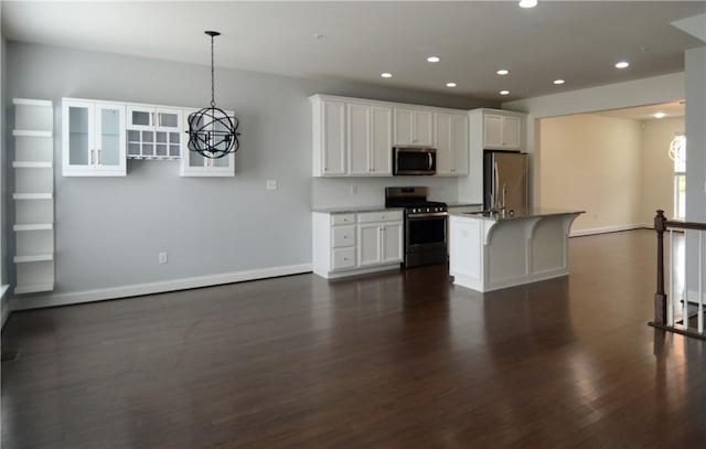 kitchen with dark wood finished floors, appliances with stainless steel finishes, white cabinets, and a notable chandelier