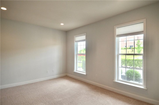 empty room featuring light carpet, baseboards, and recessed lighting