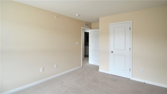 empty room featuring light carpet, baseboards, and visible vents