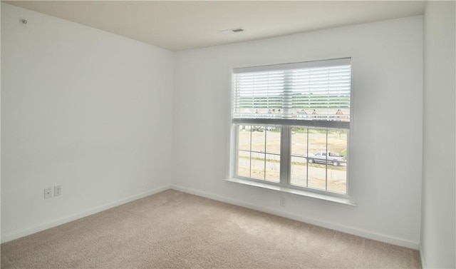 carpeted spare room with a wealth of natural light, visible vents, and baseboards
