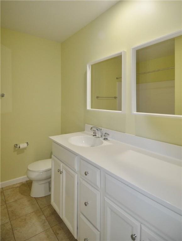 bathroom featuring tile patterned floors, toilet, baseboards, and vanity