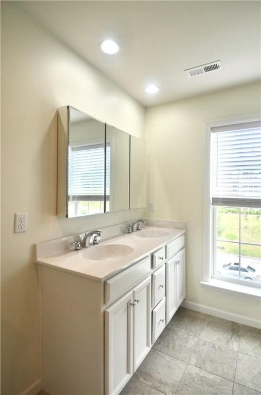 full bath with a sink, double vanity, baseboards, and visible vents