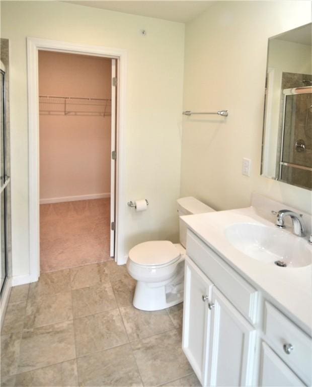 bathroom featuring a stall shower, vanity, toilet, and a spacious closet
